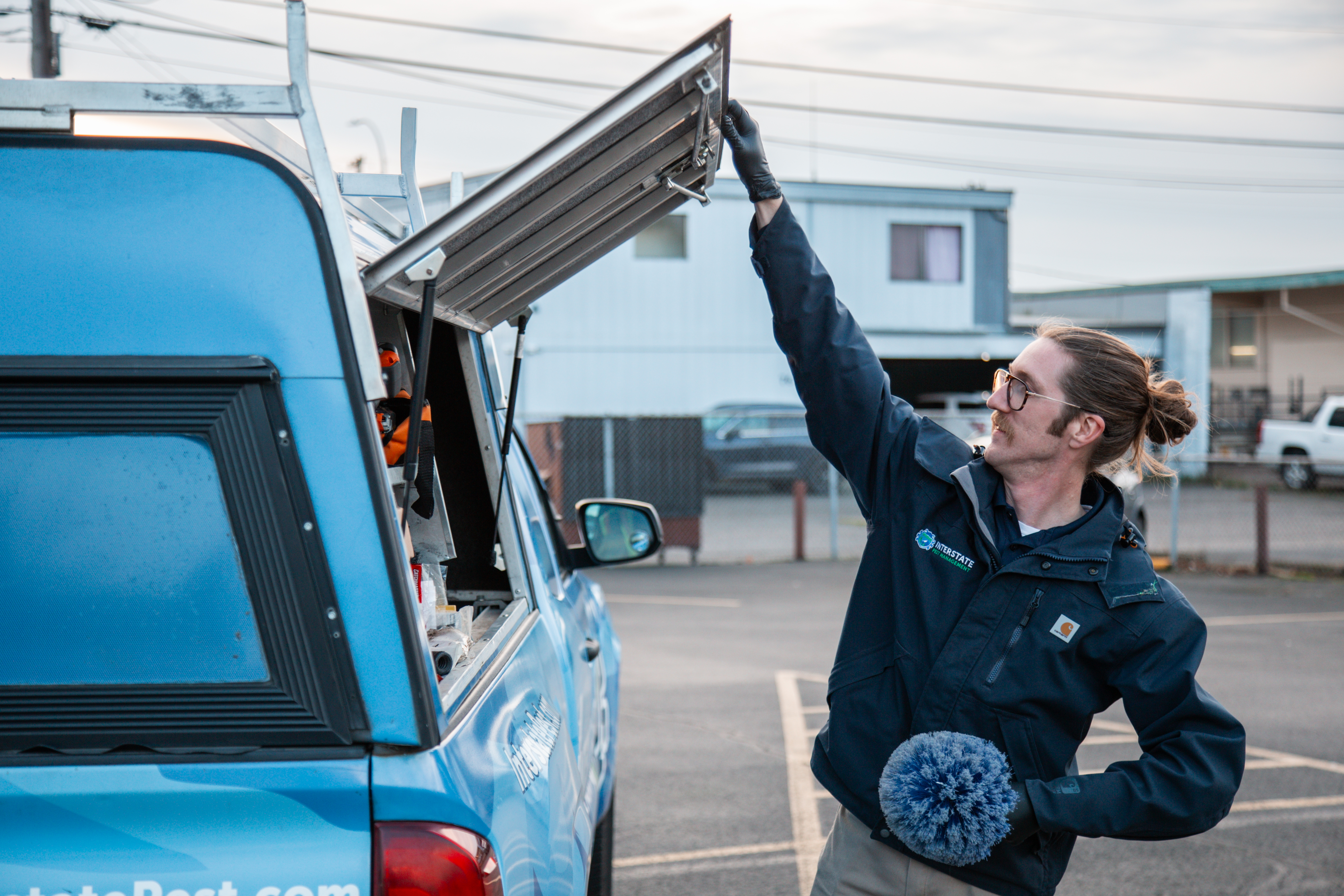 Interstate Pest Management technician removing equipment from a blue service truck toolbox