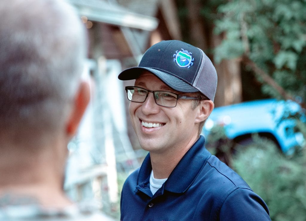 Interstate Pest Management technician in uniform talking with a homeowner in their yard before starting a service visit