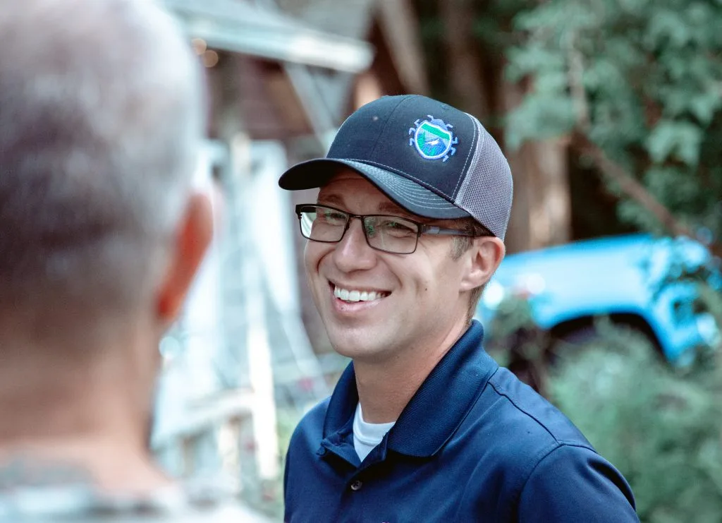 Interstate Pest Management technician in uniform talking with a homeowner in their yard before starting a service visit